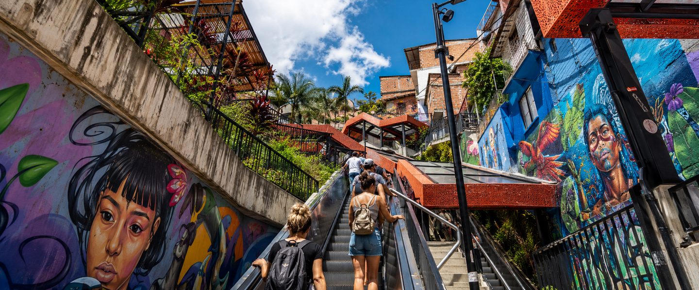 Tourists ascending escalators surrounded by graffiti on every surface
